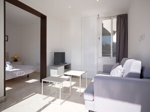 Une chambre à coucher moderne et minimaliste, comprenant un lit, une table de chevet et un téléviseur.