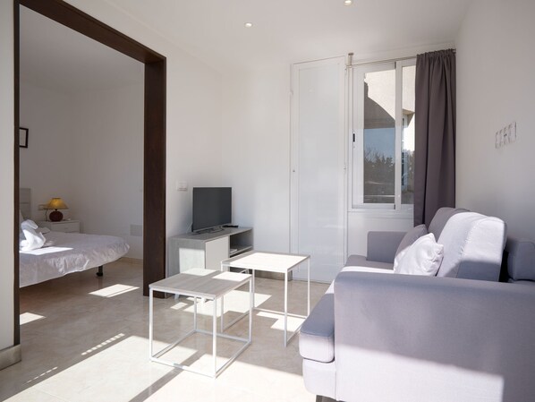 A modern, minimalist bedroom with a bed, bedside table, and a television.