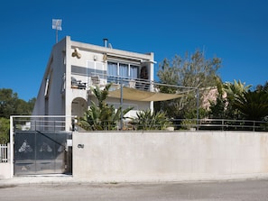 A modern two-story building with a balcony, a satellite dish, and a flag on the roof.