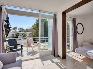 A modern hotel room with a balcony, a bed, a chair, and a small table. - 3-bedroom villa near the sea (Alcúdia)
