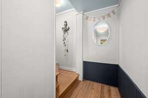 Un escalier avec des marches en bois, un grand miroir rond fixé au mur et une banderole de bienvenue.