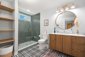 Une salle de bain moderne équipée d’une douche, de toilettes, d’un meuble-lavabo et d’un grand miroir.