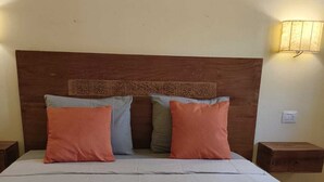 A neatly made bed with a wooden headboard, multiple pillows, and green towels on the bed. - Marialva Tropical T2 (Santa Maria)