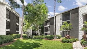 Un immeuble d’appartements moderne doté de nombreux balcons, d’une pelouse bien entretenue et d’un chemin en briques.