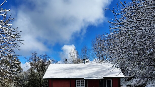 A red house with a snow-covered roof and a clear blue sky. - Charming 1-bedroom house in serene Yokuts Valley with WiFi, AC (Yokuts Valley)
