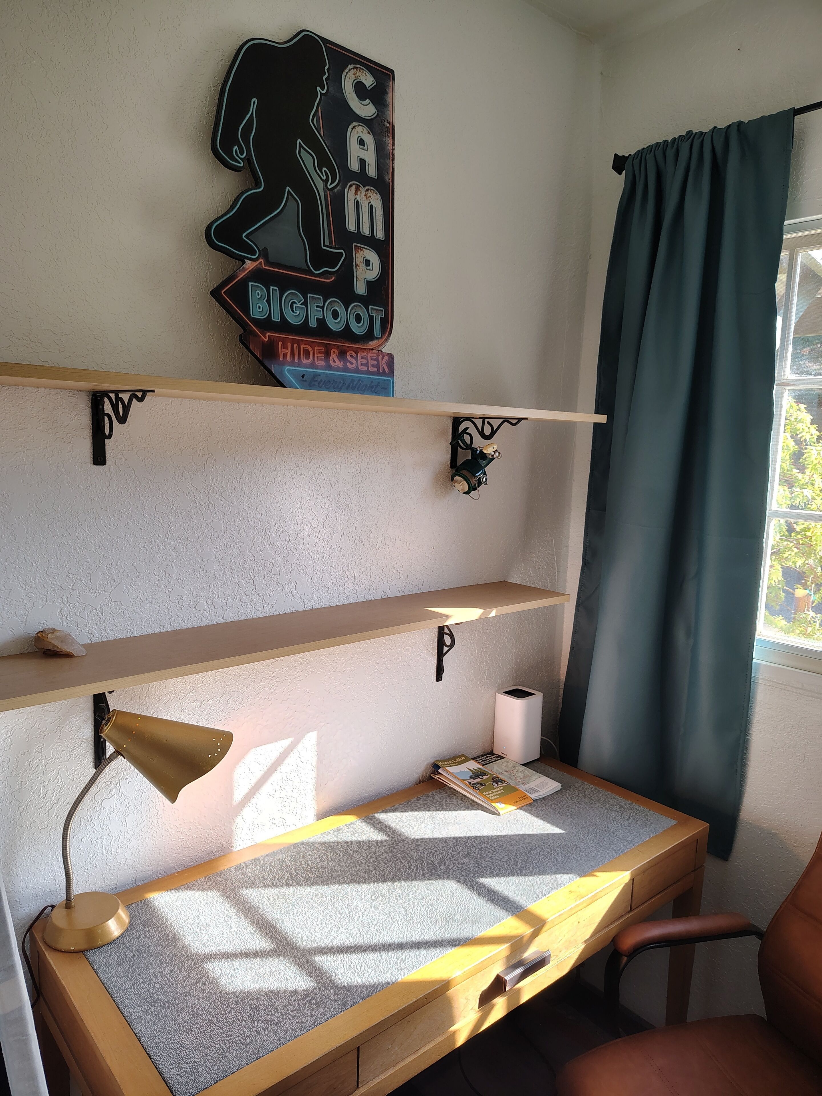 Ein Arbeitsbereich mit Schreibtisch, Regalen, einer Lampe und einem dekorativen Schild.