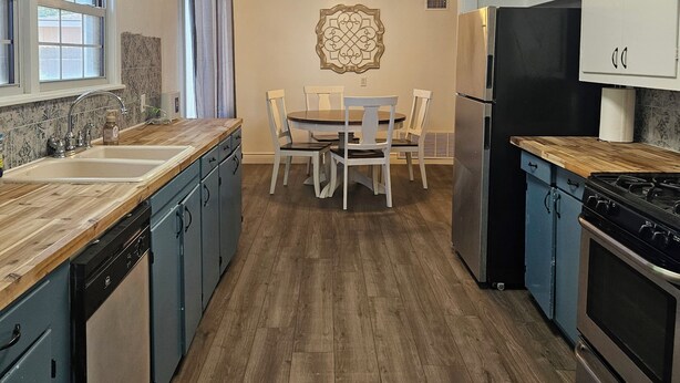 A modern kitchen with wooden countertops, a central island, and built-in appliances.
