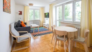 Una sala moderna con sofá, sillones, una mesa de comedor y ventanas amplias.