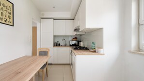A compact kitchen with white cabinets, a wooden dining table, and a built-in stove.