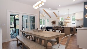Cozinha moderna com ilha central, mesa de jantar de madeira e banquetas para bar.