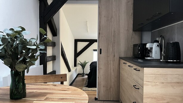 Une cuisine moderne avec des meubles en bois, une machine à café et une plante sur le plan de travail.
