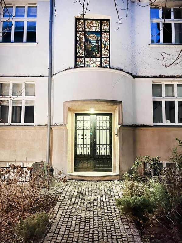 A building with a large, ornate stained glass window above a black metal gate.