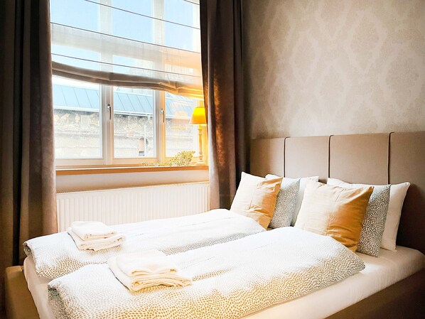 Ein Hotelzimmer mit zwei Betten, einem fensterbelaubten Fenster, einem Heizkörper und einer Lampe.