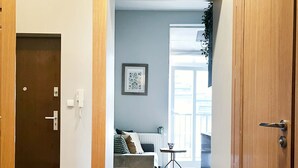 A hallway with a wooden door, a radiator, a framed picture, and a window with a view.