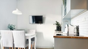 A modern kitchen with white cabinetry, a built-in oven, a sink, and a countertop with a kettle and coffee maker.