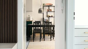 Eine moderne Küche mit Essbereich, Holzboden und einer weißen Wand mit einem dekorativen Wandpaneel.