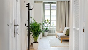 A hallway leading to a living room with a sofa, a coffee table, and a potted plant.