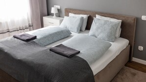 A neatly made bed with a striped blanket, a pillow, and a folded blanket on the side.
