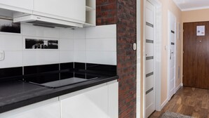 A modern kitchen with white cabinets, a black countertop, and a brick accent wall.