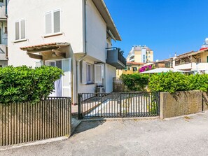 A residential building with a gated entrance, a balcony, and a small garden area. - Casa Rico by Interhome (Cecina)