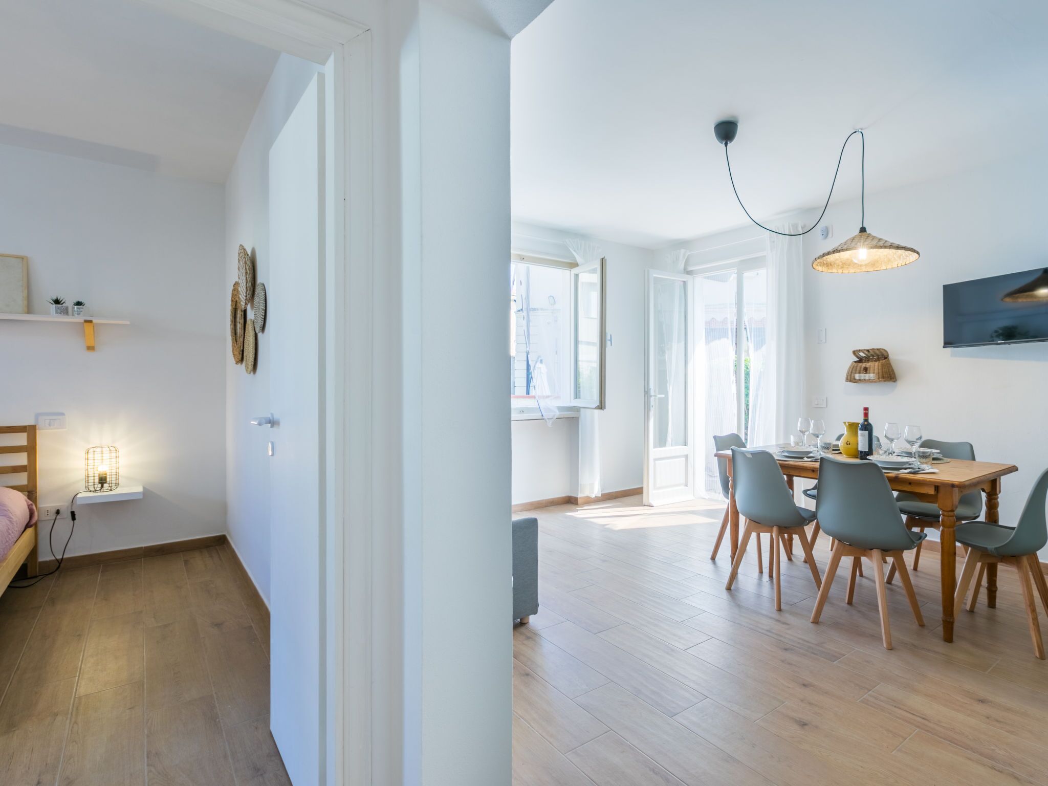 A modern apartment with a dining area, a kitchen, and a bedroom.