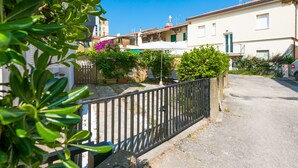 Un carrer residencial amb cases, un camí pavimentat i una tanca metàl·lica.