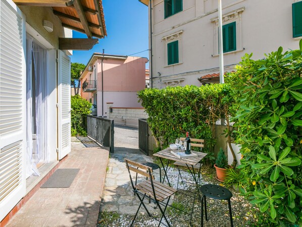 A narrow courtyard with a table and chairs, a bench, and a potted plant. - Casa Rico by Interhome (Cecina)