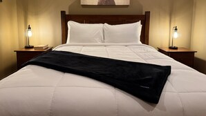 A hotel room with a large bed, two bedside lamps, a wooden headboard, and a painting of a deer on the wall.
