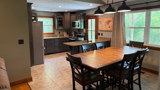 A modern kitchen with granite countertops, dark cabinetry, and a large island with bar stools.