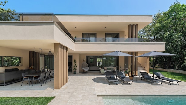 Une maison moderne à deux étages dotée d’une piscine, d’un espace salon extérieur et d’un patio couvert.