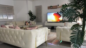 A modern living room with a white sofa, a television, and a potted plant. - Yasmine Hammamet, villa with pool near Carthage Land. (Yasmine Hammamet)