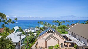 Un quartier résidentiel situé sur la côte, avec une église, un bâtiment équipé de panneaux solaires et une vue sur l’océan.