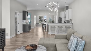 A spacious living area with a sofa, a marble coffee table, and a kitchen in the background.