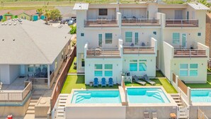 A multi-story residential building with a swimming pool, balconies, and a fenced backyard.