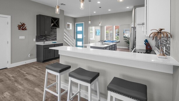A modern kitchen with a central island, bar stools, and pendant lighting.