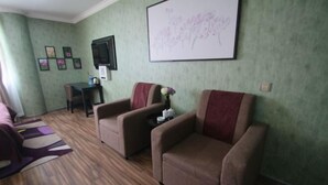 A room with a sofa, armchairs, a small table with a vase, framed pictures on the wall, and a television. - Caozihua Boutique Hotel (Shanghai Pudong New International Expo Center/World Expo Area) (Shanghai)