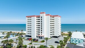 Un hôtel à plusieurs étages, doté d’une façade blanche et de touches de couleur rouge, situé près d’une plage et offrant une vue dégagée sur l’océan.