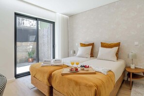 Une chambre d’hôtel moderne avec un grand lit, deux oreillers, une table de chevet avec une lampe et un plateau avec le petit-déjeuner.