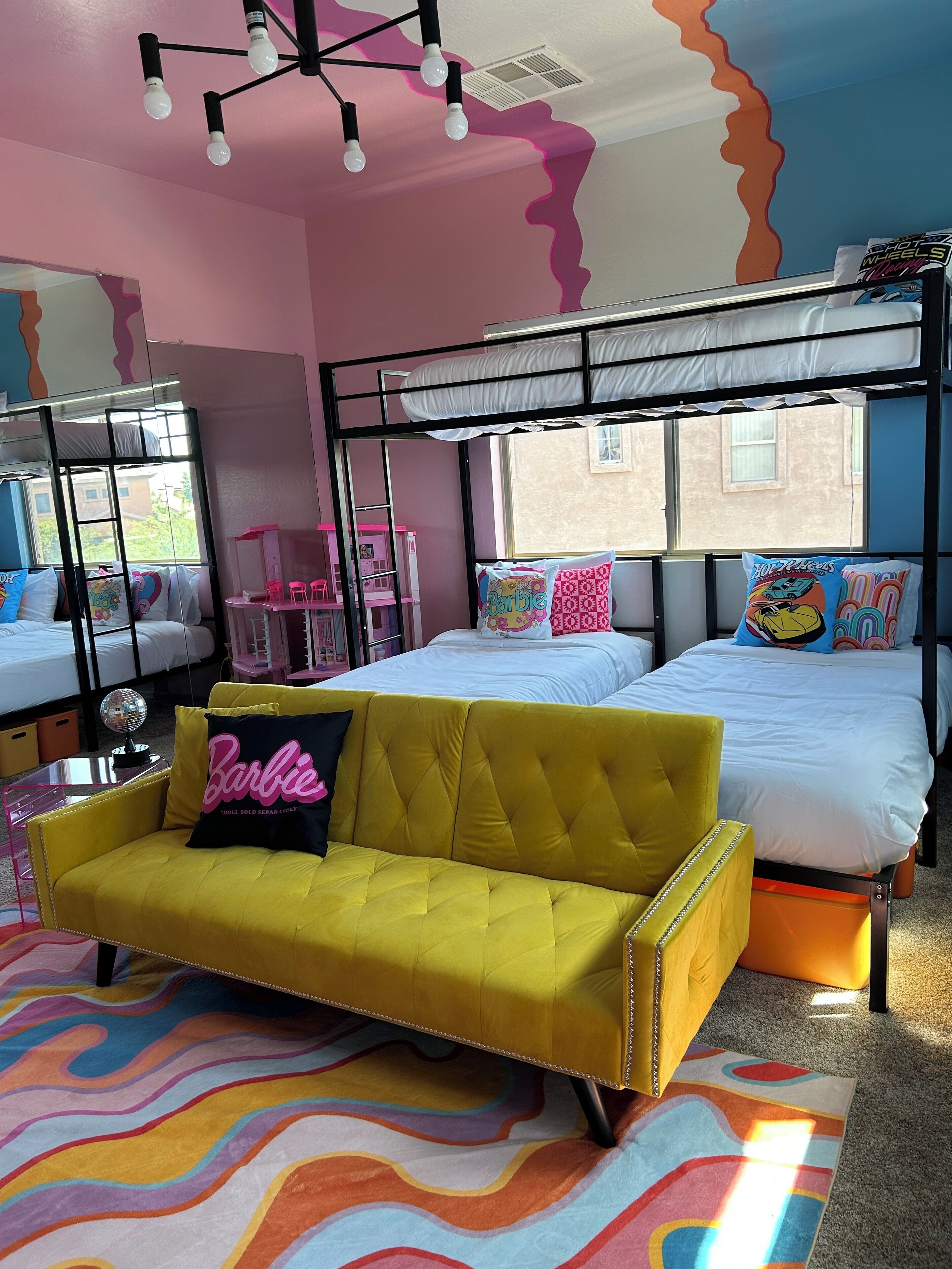 A room with bunk beds, a yellow sofa, and colorful wall art.