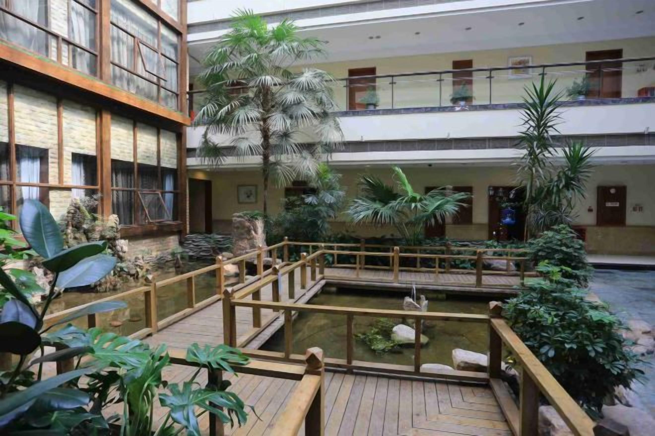 Un atrium de diversos nivells amb un terra de fusta, una font d'aigua i plantes d'interior.
