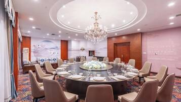 A conference room with a round table, chairs, and a chandelier.