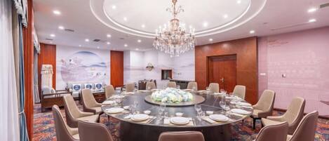 A conference room with a round table, chairs, and a chandelier.