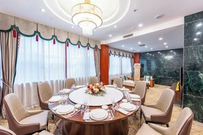 Un salón de conferencias con una mesa redonda, sillas y una araña.
