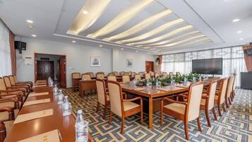 A conference room with a long table, chairs, and a television screen.