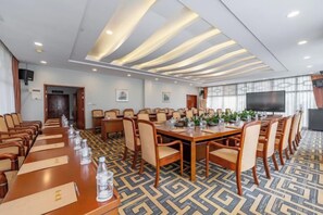 Une salle de conférence avec une longue table, des chaises et un écran de télévision.