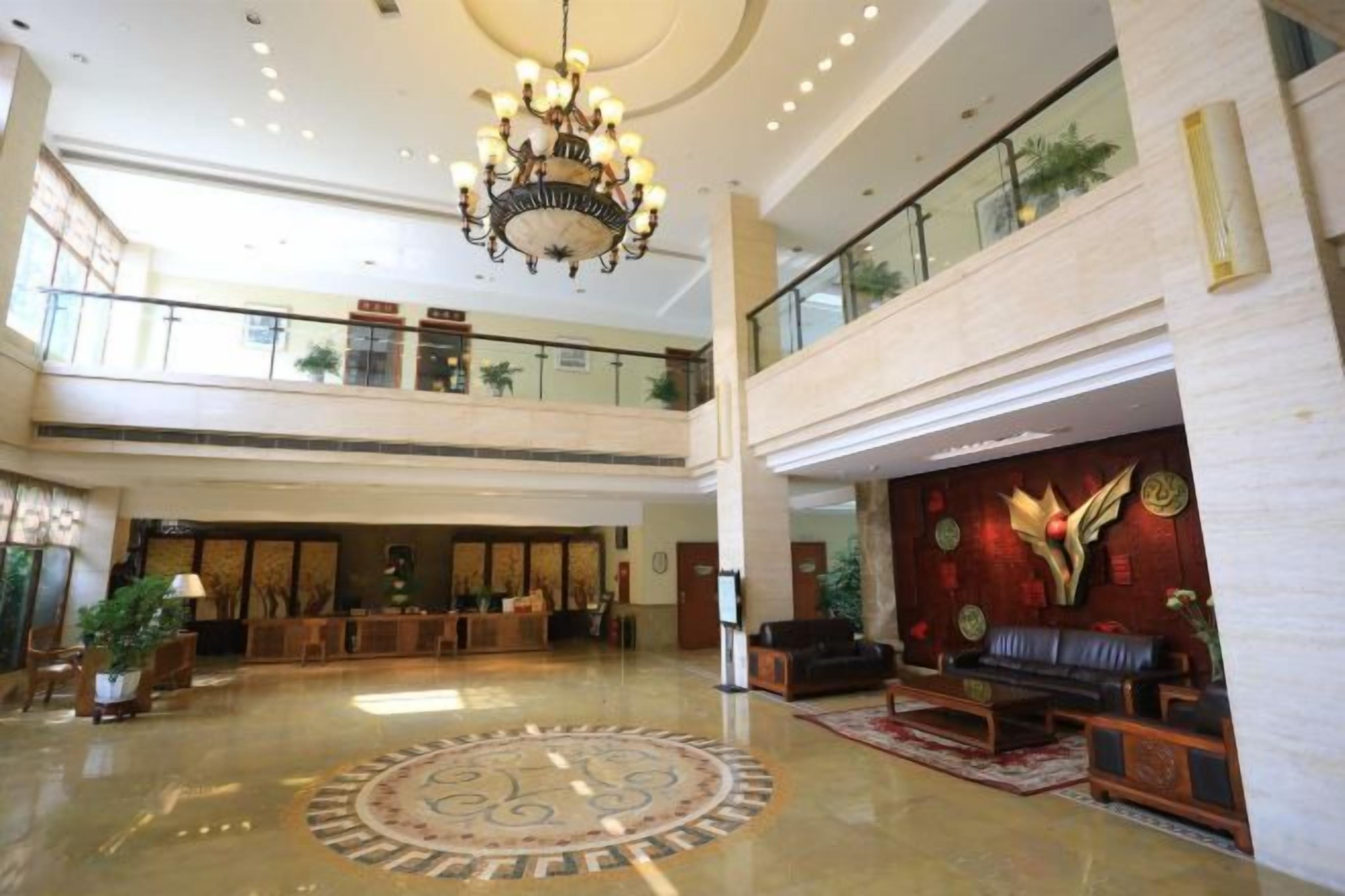 Un vestíbulo amplio con un candelabro, una recepción y una zona de estar.