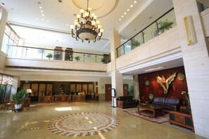 En rummelig lobby med en lysekrone, en receptionsdisk og et siddeområde.