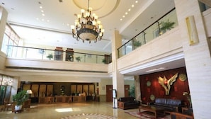 Un lobby espacioso con una araña, una recepción y un área de descanso con un muro decorativo.