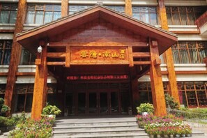 Un bâtiment en bois sur lequel est apposée une enseigne indiquant « Lijiang · Complexe hôtelier de Nanshan ».
