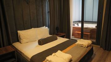 Une chambre d’hôtel avec un grand lit, une tête de lit en bois, une petite table en bois et une vue sur un jacuzzi.
